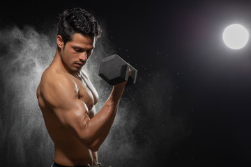 Man working out with dumbbells over a dark background. 
