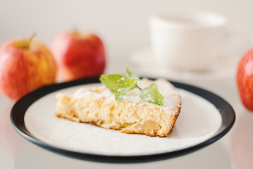 Apple pie with powdered sugar and fresh mint leaves served with whole apples and a cup of tea. Simple apple pie recipe