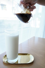 Pouring hot coffee into a glass of cold milk..Coffee is pouring into a glass with milkshake.