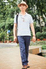 Senior Chinese man in casual clothes enjoying walking in park on warm summer day