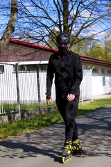 A young man rides a rollerblade during a coronavirus pandemic. He has a mask. A man in a tracksuit...