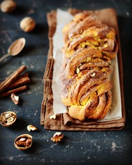 Cinnamon twisted loaf bread or babka on a dark wooden background, still life, rustic style