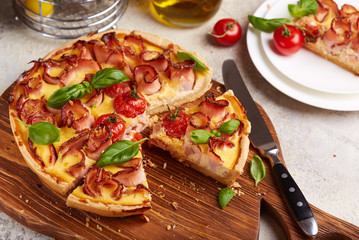 Quiche open tart pie with ham and tomatoes filled with cream, cheese and eggs. Savory taste.