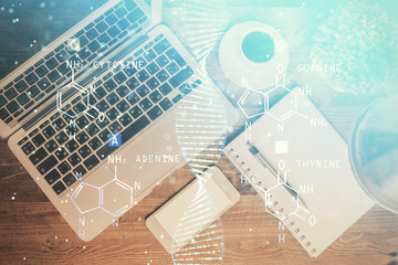 DNA hologram drawings over computer on the desktop background. Top view. Multi exposure. Concept medical education.