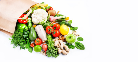 Healthy vegan vegetarian food in full paper bag, vegetables and fruits on white background, copy space, banner. Shopping food supermarket, groceries and clean eating concept. Healthy food background