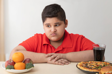 Young boy looking disgustingly at fruits and vegetables. (Obesity) 	