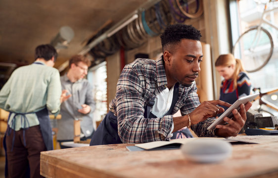 Male Craftsman In Carpentry Workshop For Bamboo Bicycles Using Digital Tablet And Smart Speaker