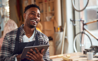 Male Craftsman In Carpentry Workshop For Bamboo Bicycles Using Digital Tablet 