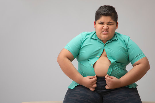 Young boy struggling to fit in a tight shirt. (Obesity)	