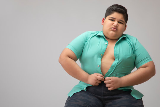 Young boy struggling to fit in a tight shirt. (Obesity)	