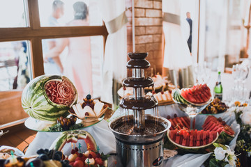 chocolate fountain and red watermelon. catering services in restaurant outdoor on wedding ceremony. Food and glass of champagne. restaurant
