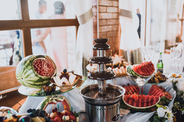 chocolate fountain and red watermelon. catering services in restaurant outdoor on wedding ceremony. Food and glass of champagne. restaurant