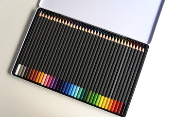 Estuche de lápices de colores. Cuerpo oscuro. Lápices de madera, ordenados según los colores del arco iris. Material escolar y de dibujo.