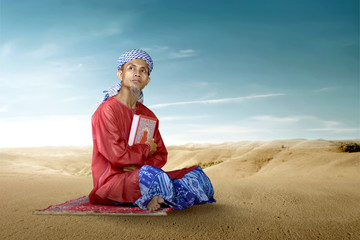 Fototapeta na wymiar Asian Muslim man sitting and holding the Quran