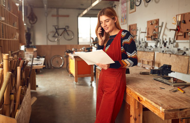 Female Craftsman In Carpentry Workshop For Bamboo Bicycles Making Call On Mobile Phone