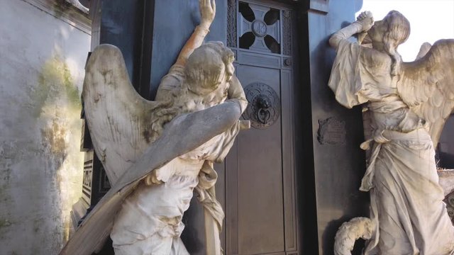 Two sculptured angles at door of black mausoleum crypt in Buenos Aires cemetery
