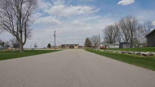 POV while driving past playground towards the local school in rural Illinois community in early spring