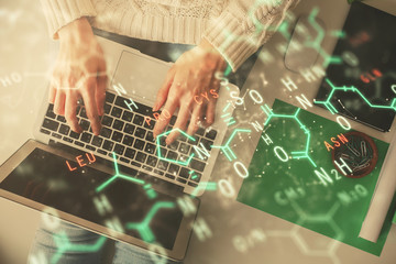 Double exposure of woman hands working on computer and formula hologram drawing. Top View. Science concept.