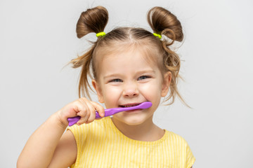 child in a yellow T-shirt with clean teeth brushing on a light background