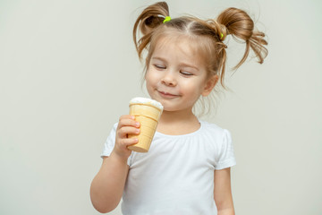 3-4 years old girl in a white T-shirt eating ice cream and smiling. children and sweets