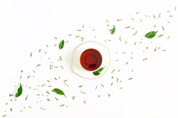 Ceramic cup of brewed tea, fresh green leaves and dried herbal scattered on white background....