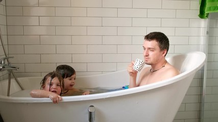 Father drinks coffee in the bathroom where children splash - Powered by Adobe