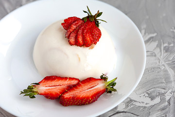 italian dessert panna cotta with fresh strawberries and a banana on a grey concrete background