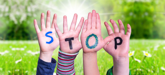 Kids Hands Holding Colorful English Word Stop. Sunny Green Grass Meadow As Background