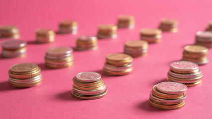 Close up piled coins in lines on pink background. Money saving financial concept. Economic crisis. Save the money