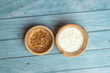Bowl of whole grain muesli with yogurt on blue wooden background, flat lay top view angel, morning food concept