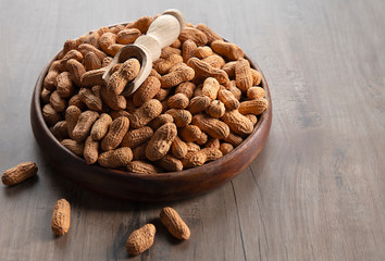 Groundnuts in a wooden plate with a wooden spoon. 
