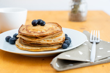Homemade pancakes arranged on a white plate with blueberries - Copy space