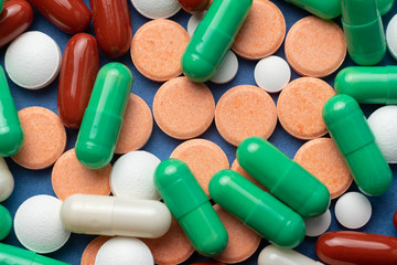 many multi-colored medical pills on blue background close-up