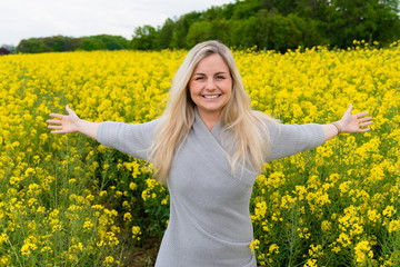 Young woman suffers from allergy in a rape field and has to sneeze