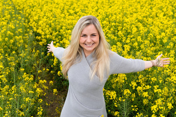 Young woman suffers from allergy in a rape field and has to sneeze