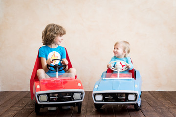 Superheroes children driving toy cars at home