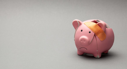 Broken piggy bank with band-aid on gray background - Powered by Adobe