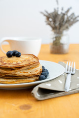 Homemade pancakes arranged on a white plate with blueberries - Copy space