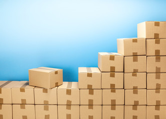 Cardboard boxes steps up for delivery or moving. Stack of boxes and blue background. Copy space for text