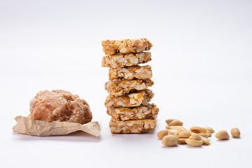 Jaggery and mungfali chikki kept alongside plain peanuts on a white background.
