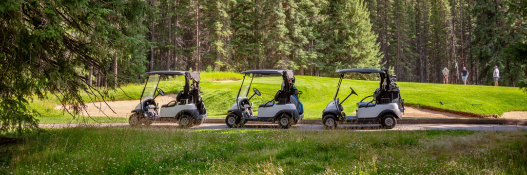 Row of empty electric carts on the side of the golf course, in Banff, Alberta, Canada