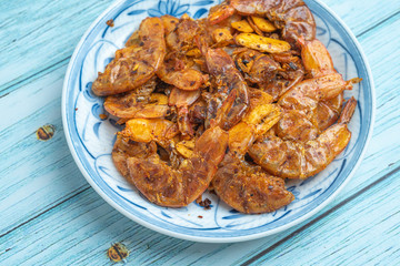Thai food, Fried Crispy shrimp with herbs and spices on old ceramic dish with Blue Wooden Background , Flat Lay Out, Top View Angle