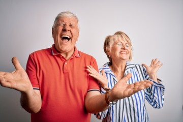 Senior beautiful couple standing together over isolated white background celebrating mad and crazy for success with arms raised and closed eyes screaming excited. Winner concept