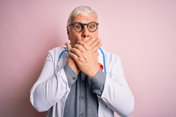 Senior handsome hoary doctor man wearing stethoscope and red HIV ribbon on coat shocked covering mouth with hands for mistake. Secret concept.