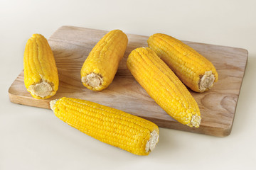 boiled corn on a cutting board on a light background, selective focus