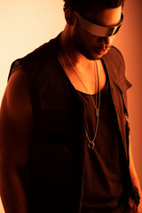 stylish african american man posing in futuristic sunglasses on orange