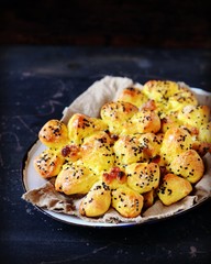 Homemade buns with raisins and sesame seeds on a dark blue wooden background