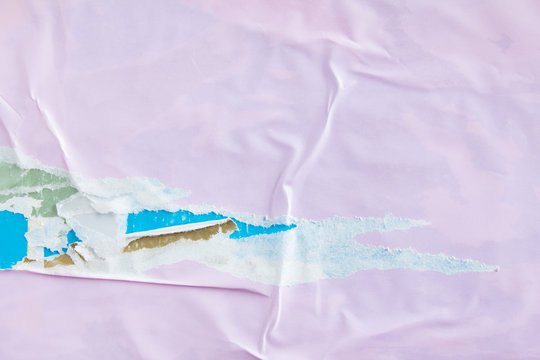 Pink torn and crumpled glossy placards on urban billboard with old ripped and peeling paper posters texture background.