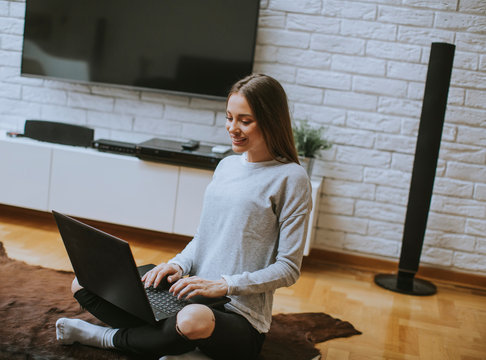 Young yoman websurfing with laptop on the floor in apartment