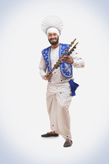 Portrait Of Sikh man Dancing and Holding A Chimta
